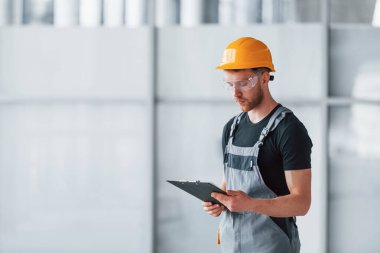 Gri üniformalı genç bir mühendis. Gündüz vakti modern büyük ofiste çalışıyor..