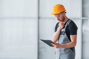 Gri üniformalı genç bir mühendis. Gündüz vakti modern büyük ofiste çalışıyor..