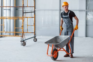 El arabalarıyla yürüyor. Gri üniformalı adam gündüz vakti modern büyük ofiste çalışıyor..