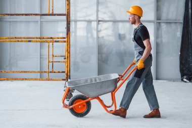 El arabalarıyla yürüyor. Gri üniformalı adam gündüz vakti modern büyük ofiste çalışıyor..