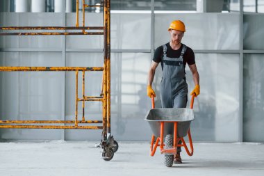 El arabalarıyla yürüyor. Gri üniformalı adam gündüz vakti modern büyük ofiste çalışıyor..