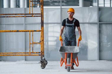 El arabalarıyla yürüyor. Gri üniformalı adam gündüz vakti modern büyük ofiste çalışıyor..