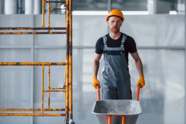 El arabalarıyla yürüyor. Gri üniformalı adam gündüz vakti modern büyük ofiste çalışıyor..