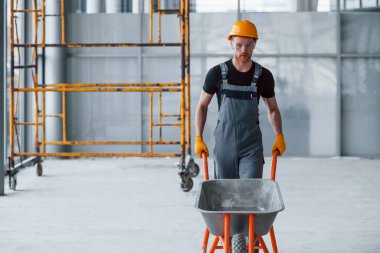 El arabalarıyla yürüyor. Gri üniformalı adam gündüz vakti modern büyük ofiste çalışıyor..