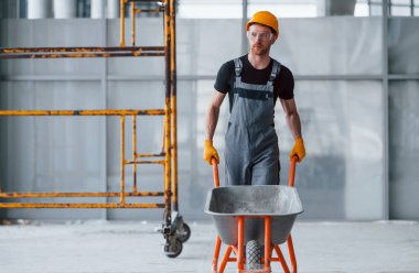 El arabalarıyla yürüyor. Gri üniformalı adam gündüz vakti modern büyük ofiste çalışıyor..