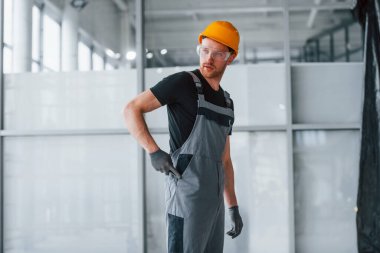 Gri üniformalı adam gündüz vakti modern büyük ofiste çalışıyor..