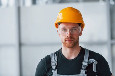 Gri üniformalı, koruyucu gözlüklü ve turuncu şapkalı bir adamın portresi..