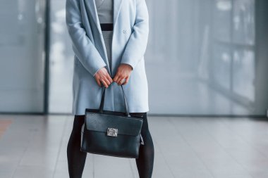 Gri arka planda siyah çantalı şık elbiseli güzel bir sarışın..