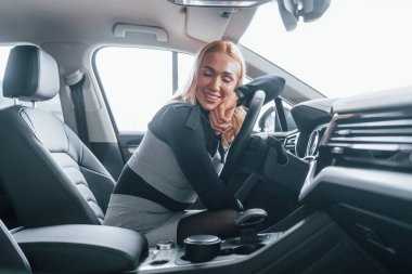 Modern arabanın içinde oturan zarif elbiseli güzel sarışının yan görüntüsü..