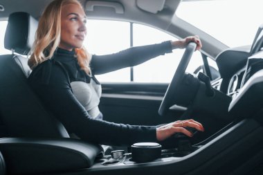 Modern arabanın içinde oturan zarif elbiseli güzel sarışının yan görüntüsü..