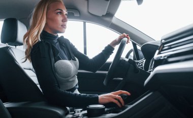 Modern arabanın içinde oturan zarif elbiseli güzel sarışının yan görüntüsü..