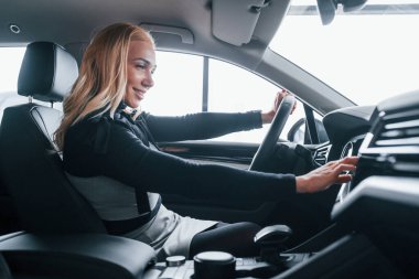 Modern arabanın içinde oturan zarif elbiseli güzel sarışının yan görüntüsü..