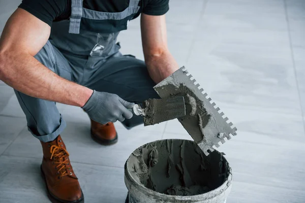 Gri üniformalı adam gündüz vakti modern büyük ofiste kapalı alanda çalışıyor..