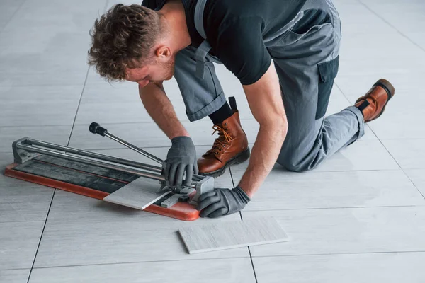 Gri üniformalı bir adam modern büyük ofiste gündüz vakti içeri tabak yerleştiriyor..