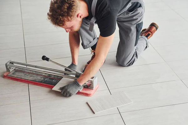 Gri üniformalı bir adam modern büyük ofiste gündüz vakti içeri tabak yerleştiriyor..