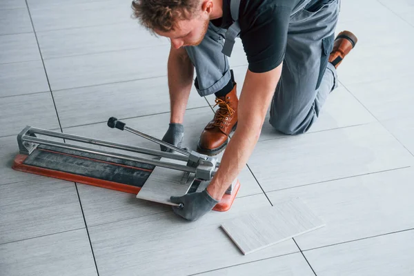 Gri üniformalı bir adam modern büyük ofiste gündüz vakti içeri tabak yerleştiriyor..