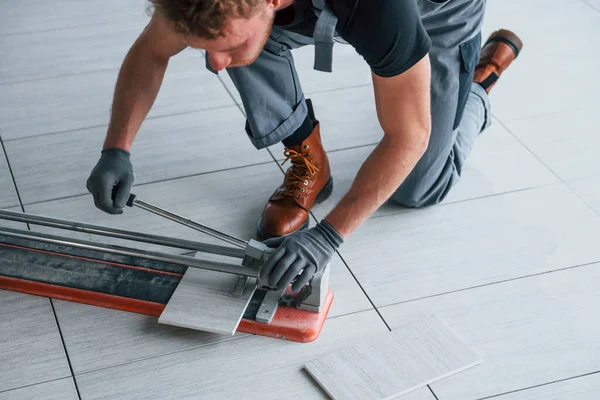 Gri üniformalı bir adam modern büyük ofiste gündüz vakti içeri tabak yerleştiriyor..