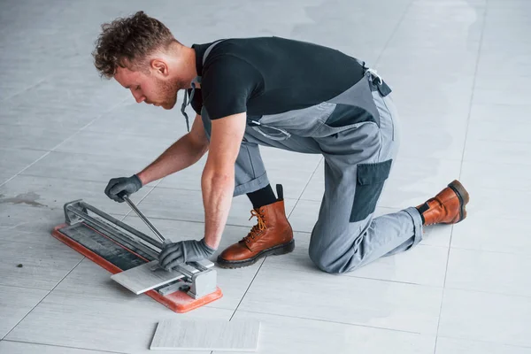 Gri üniformalı bir adam modern büyük ofiste gündüz vakti içeri tabak yerleştiriyor..