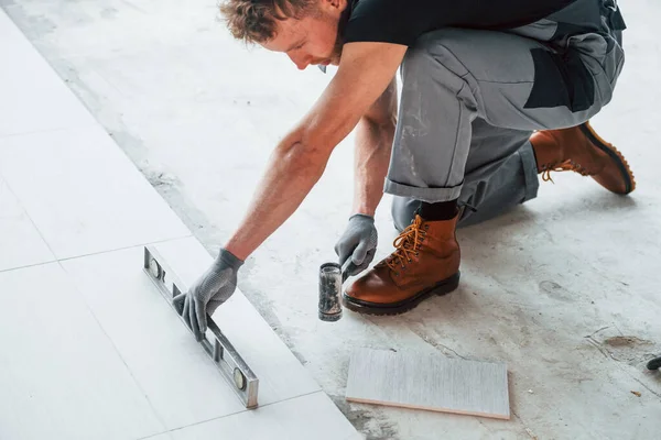 Gri üniformalı bir adam modern büyük ofiste gündüz vakti içeri tabak yerleştiriyor..