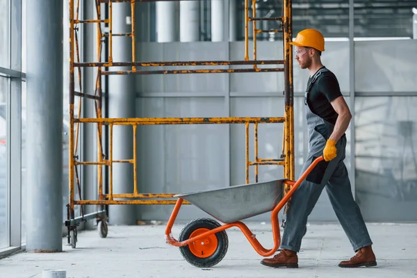 El arabalarıyla yürüyor. Gri üniformalı adam gündüz vakti modern büyük ofiste çalışıyor..