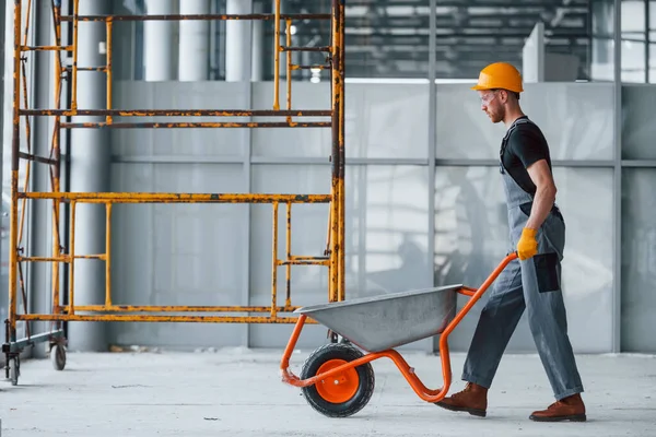 El arabalarıyla yürüyor. Gri üniformalı adam gündüz vakti modern büyük ofiste çalışıyor..