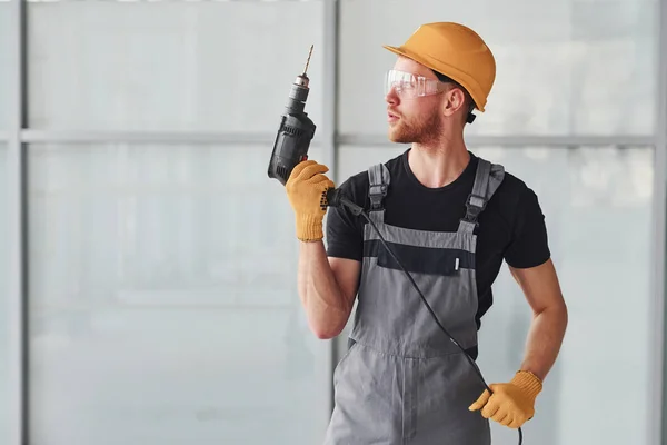 Mann Grauer Uniform Mit Bohrer Der Hand Steht Tagsüber Drinnen — Stockfoto