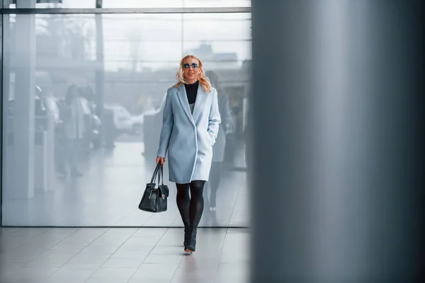 Beautiful Blonde Elegant Clothes Black Handbag Standing Indoors Grey Background — Zdjęcie stockowe