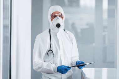 Laboratuvar önlüklü, koruyucu gözlüklü ve maskeli bir erkek doktor..