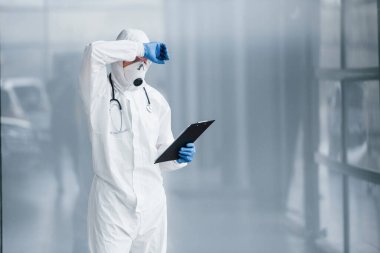 Laboratuvar önlüklü, koruyucu gözlüklü ve maskeli bilim adamı ara verdi..