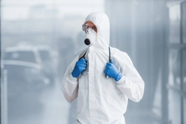 Laboratuvar önlüklü, koruyucu gözlüklü ve maskeli bir erkek doktor..