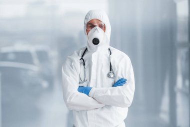 Laboratuvar önlüklü, koruyucu gözlüklü ve maskeli bir erkek doktor..