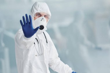 El hareketlerini durdurur. Laboratuvar önlüklü, koruyucu gözlüklü ve maskeli bir erkek doktor..