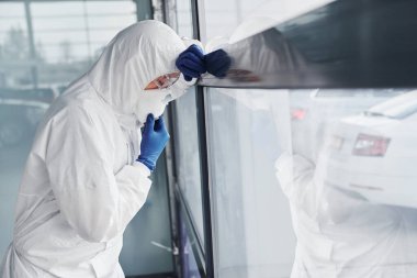 Male doctor scientist in lab coat, defensive eyewear and mask feels bad, exhausted and sick.