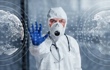 Digital world map on picture. Male doctor scientist in lab coat, defensive eyewear and mask standing indoors.