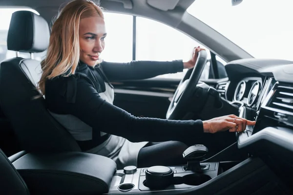 Modern arabanın içinde oturan zarif elbiseli güzel sarışının yan görüntüsü..