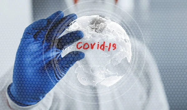 男性医師科学者でラボコートとマスク立って屋内で世界地図でCovid 19単語 — ストック写真