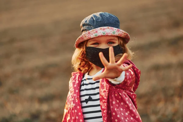 Showing Hand Portrait Cute Little Girl Black Protective Mask Standing — стоковое фото