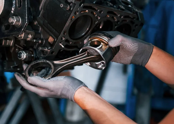 Professional repairman works with broken automobile engine.