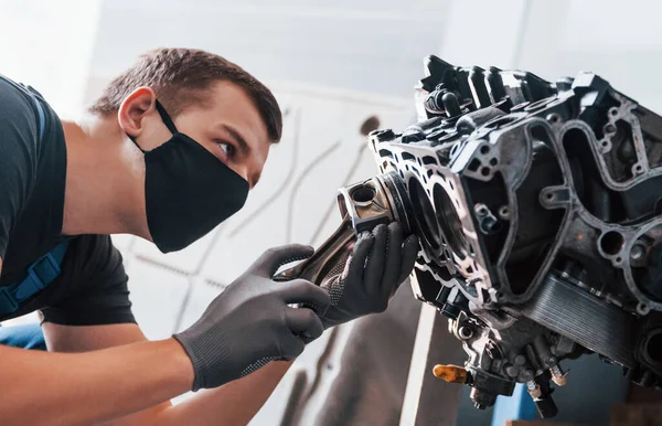 Siyah koruyucu maskeli profesyonel tamirci bozuk otomobil motoruyla çalışır..
