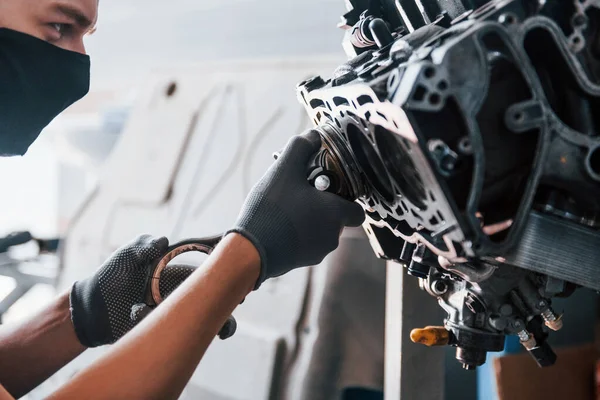 Siyah koruyucu maskeli profesyonel tamirci bozuk otomobil motoruyla çalışır..