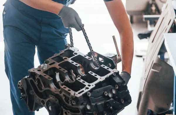 Professional repairman works with broken automobile engine.