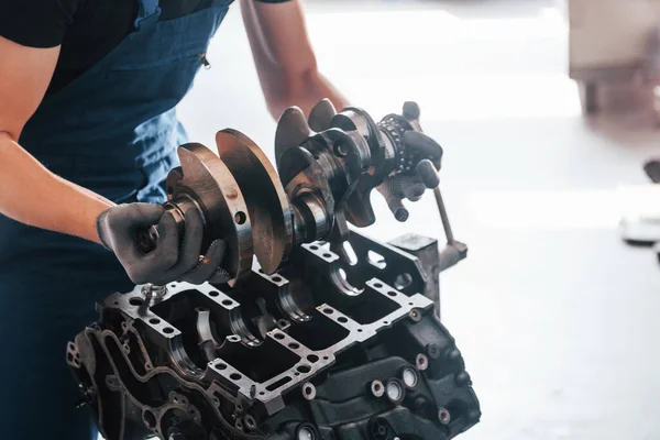 Professional repairman works with broken automobile engine.