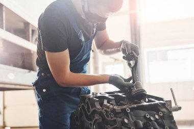 Güzel ışıklandırma. Siyah koruyucu maskeli profesyonel tamirci bozuk otomobil motoruyla çalışır..