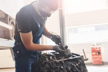 Güzel ışıklandırma. Siyah koruyucu maskeli profesyonel tamirci bozuk otomobil motoruyla çalışır..