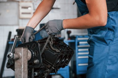 Close up view of professional repairman in garage that works with broken automobile engine.