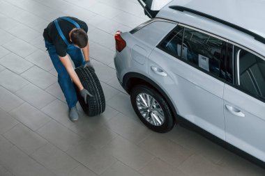 Siyah-mavi üniformalı işçilerin en iyi görüntüsü. Araba tekeri kapalı alanda çalışıyor..