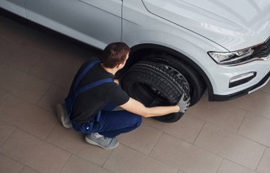 Siyah-mavi üniformalı işçilerin en iyi görüntüsü. Araba tekeri kapalı alanda çalışıyor..