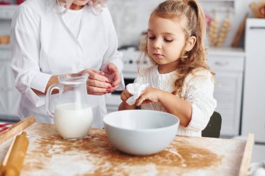 İçi süt dolu. Büyük büyükanne ve küçük torunu mutfakta Noel için tatlı pişiriyor..