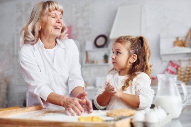Öğretim süreci. Büyük büyükanne ve küçük torunu mutfakta Noel için tatlı pişiriyor..