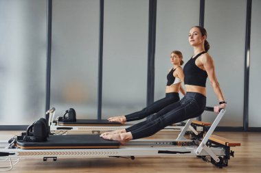 Hands strength. Two women in sportive wear and with slim bodies have fitness yoga day indoors together.